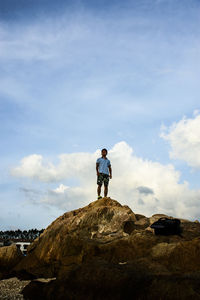 Rear view of man standing on rock against sky