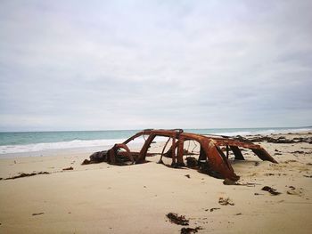 Abandoned rusty on beach against sky