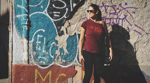 Woman standing against graffiti wall
