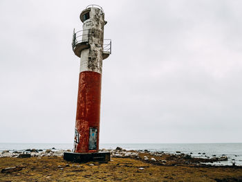 Lighthouse by sea against sky