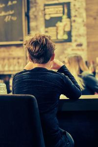 Rear view of boy sitting at table in restaurant