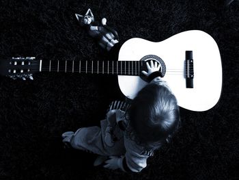 High angle view of child sitting by acoustic guitar on rug