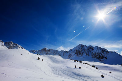 Scenic view of snow covered mountains against blue sky