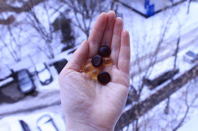 Cropped hand holding omega vitamins on the background of winter city