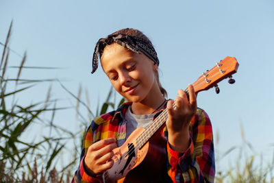 Girl with guitar. teen girl walking on nature background. little kid girl outside on green meadow. 