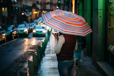 Rear view of woman walking on street during rainy season