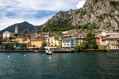 Buildings at waterfront against cloudy sky