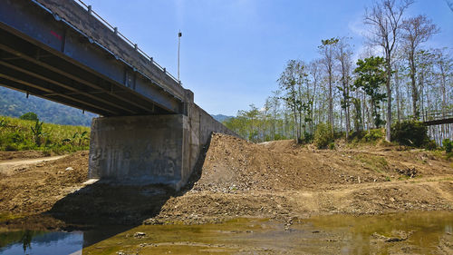 Bridge over river amidst trees against sky