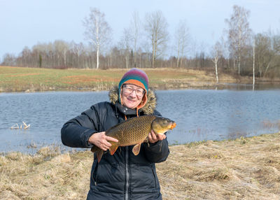 A happy fisherman on the lake shore, caught carp in a woman's hand, amateur carp fishing