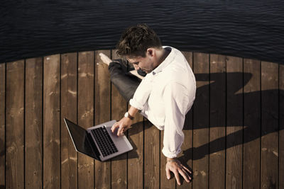 High angle view of businessman using laptop on boardwalk