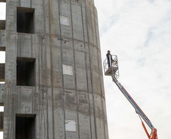 Low angle view of man working at construction site against sky