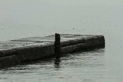 Wooden posts in sea against sky