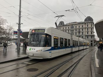 Cars on railroad station in city against sky