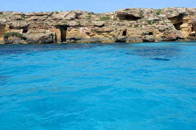 Rock formations in sea against blue sky