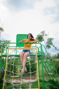 Smiling woman sitting on outdoor play equipment