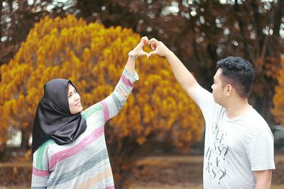 Couple making heart shape with hands during autumn at park