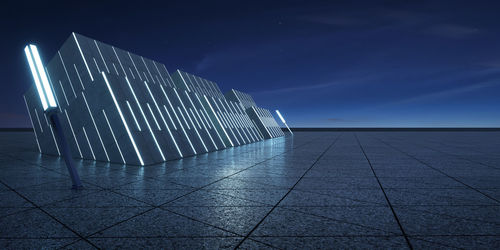 Illuminated footpath against blue sky at night