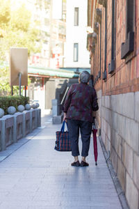 Rear view of woman walking on footpath