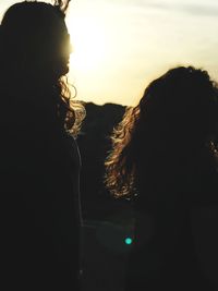 Rear view of silhouette woman standing against sky during sunset