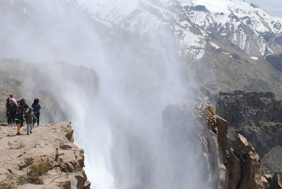 People on mountain by waterfall