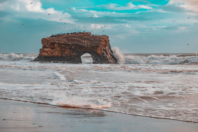 Rock formation on sea shore against sky