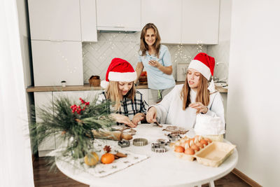 Mom and her daughters cook christmas cookies or gingerbread together, family cooking of festive