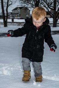 Full length portrait of smiling girl playing in snow