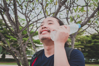 Close-up of smiling man touching bottle on face