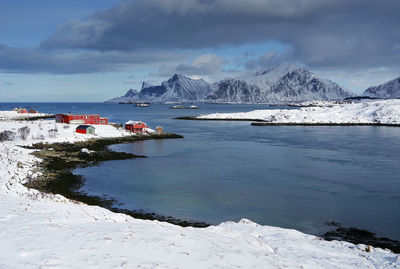 Scenic view of sea by snowcapped mountains against sky