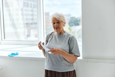 Woman standing against window at home