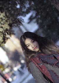 Portrait of smiling young woman standing in snow