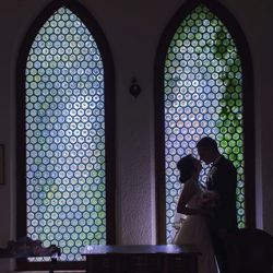 Side view of wedding couple standing face to face by window