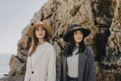 Thoughtful sisters looking away while standing at beach