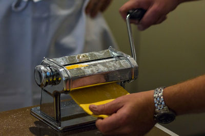 Cropped hands of man making pasta in maker