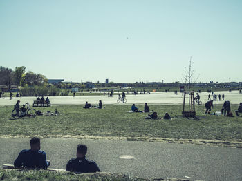 Group of people relaxing on shore against clear sky