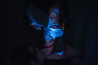 Close-up portrait of man with face paint against black background