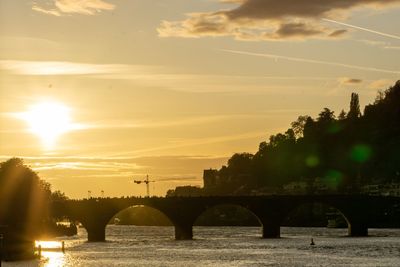 Bridge over river against sky during sunset