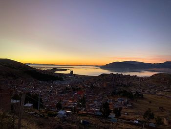 High angle view of townscape by sea against sky during sunset