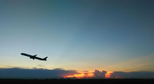 Low angle view of silhouette airplane against clear sky