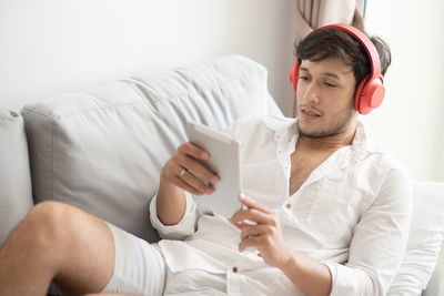 Man watching video in digital tablet while lying down on sofa