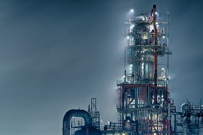 Low angle view of illuminated industry against sky at night