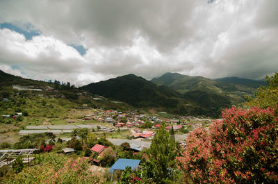 Scenic view of town by mountains against sky