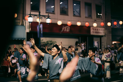 Crowd standing on illuminated street at night