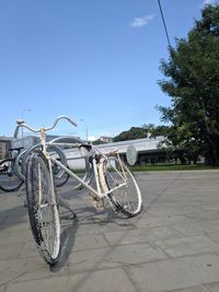 Bicycle parked on footpath against blue sky