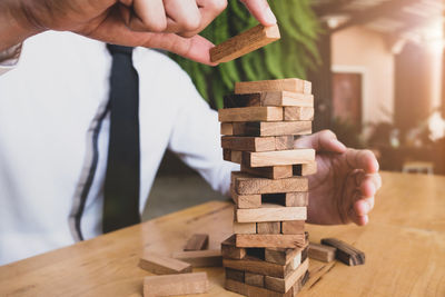 Cropped image of business person playing block removal game on table