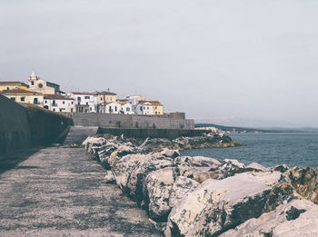 Scenic view of sea by buildings against sky