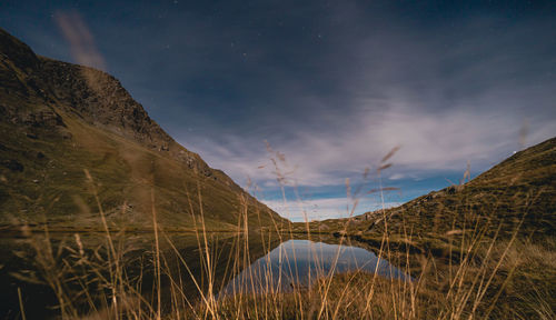 Alpine lake at night with grass at foreground