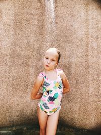 Full length of cute girl standing against wall