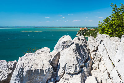 Panoramic view of rocks on shore against blue sky