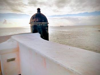 Lighthouse by sea against sky